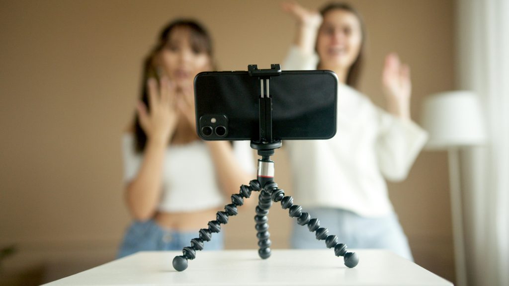 two teens filming themselves dancing using a phone mounted on a tripod